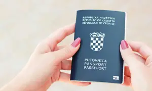 Dwie dłonie trzymają paszport Republiki Chorwacji. Czy do Chorwacji potrzebny jest paszport? Tak, ten dokument jest niezbędny do podróży.