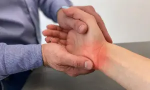 Fizjoterapeuta bada zaczerwieniony nadgarstek pacjenta, delikatnie go dotykając.
