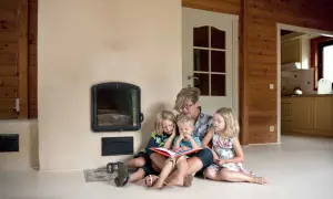 Een moeder leest voor aan haar drie kinderen bij de open haard. Een moment van rust en samenzijn, ontspullen voor en na een drukke dag.