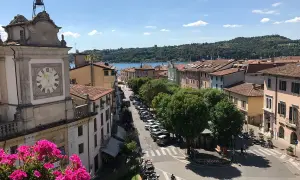 Vista dall'alto di Salò, con il lago sullo sfondo. Un orologio segna l'ora su un edificio storico.