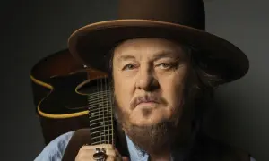 Mężczyzna w kapeluszu z gitarą, uosobienie Dire Straits Legacy.