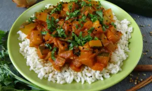 Pyszna cukinia w curry z ryżem, posypana świeżą natką pietruszki i czarnuszką. Aromatyczne danie, które zachwyci każdego.