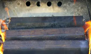 Drei Braunkohlebriketts brennen im Kaminofen. Die Flammen lodern um die Briketts.