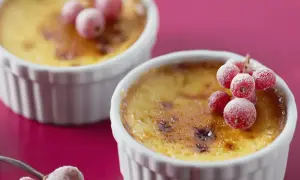 Deux flans aux œufs, dorés et caramélisés, ornés de groseilles givrées. Un délice visuel et gustatif.