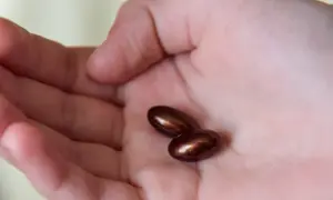 Dwie brązowe kapsułki leżą na dłoni. Kiedy przyjmować żelazo? Najlepiej na czczo lub z witaminą C.
