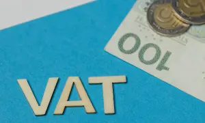 Drewniane litery VAT i polskie banknoty oraz monety. Temat: zwolnienie z VAT.