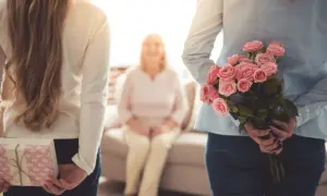 Dwie córki ukrywają prezent i bukiet róż dla mamy z okazji dnia matki.