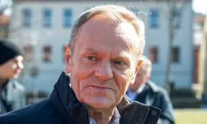 Tusk, z widocznym wiekiem, w ciemnej kurtce, na tle budynków.