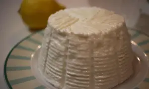 Un fiadone crémeux, prêt pour la recette des Carnets de Julie, avec un citron flou en arrière-plan.