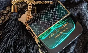 Flakon perfum Marc Jacobs Decadence w zielonym, wężowym wzorze, z czarnym frędzlem i złotym łańcuszkiem, emanuje luksusem.