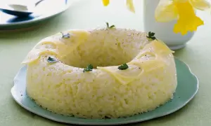 Sformato di riso a ciambella, decorato con fette di formaggio e prezzemolo, su un piatto verde.