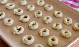 Små, ringformade taralli ligger redo på en bakplåt. Ett perfekt taralli recept för hembakade godsaker.