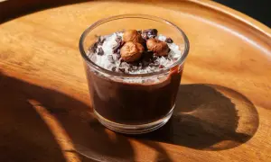 Delizioso dessert in bicchiere con yogurt, cacao, cocco grattugiato e nocciole.