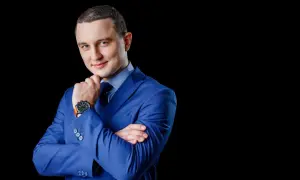 Elegancki mężczyzna w niebieskiej marynarce, z dłonią na podbródku. Profesjonalne zdjęcie do CV.