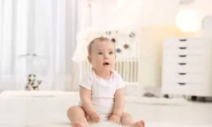Urocze dziecko z niebieskimi oczami, kiedy dziecko siada na miękkim dywanie w pokoju dziecięcym.