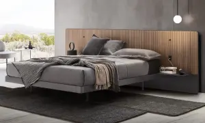 Elegante camera da letto con letto grigio e testiera in legno. Il colore grigio abbinamento crea un'atmosfera rilassante.