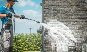 Mann reinigt Klinkerwand mit Hochdruckreiniger.