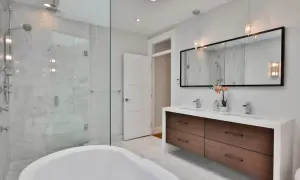 Bagno moderno con vasca freestanding, doccia in cristallo e mobile doppio lavabo con cassetti in legno. Le pareti sono rivestite in marmo, il soffitto è in cartongesso.