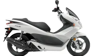 Biały skuter Honda PCX 125, znany z niskiego spalania, na białym tle.