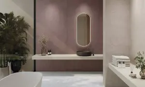 Elegante baño moderno con lavabo de piedra, espejo ovalado iluminado y azulejos de pared en tono malva. Toallas apiladas y plantas aportan calidez.