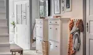 Elegante decoración de entradas y recibidores: zapateros blancos, perchero con abrigos y un banco de madera invitan a entrar.