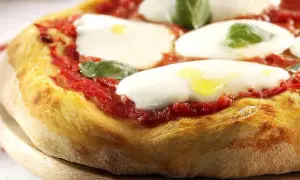 En närbild av en klassisk italiensk mat: pizza Margherita med krämig mozzarella, röd tomatsås och färsk basilika.