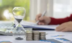 Klepsydra, monety i kalkulator symbolizują czas i finanse. Zastanawiasz się, na ile lat można wziąć kredyt gotówkowy?
