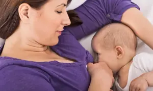 En mamma ammar sitt barn i en liggande position, en av många olika amningspositioner.