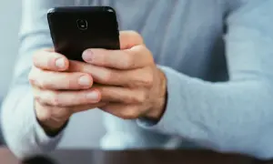 Dłonie trzymające czarny smartfon. Dowiedz się, jak się wylogować z FB na telefonie, by zadbać o prywatność.