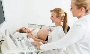 Ciężarna kobieta na USG. Czy do ginekologa trzeba mieć skierowanie od lekarza rodzinnego? Lekarka wykonuje badanie.