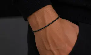 Pulsera barbada oro con diamantes negros en muñeca masculina. Elegancia y estilo en cada detalle.
