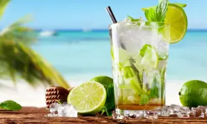 Orzeźwiający mohito alkohol z limonką i miętą na tle plaży. Idealny na wakacje!