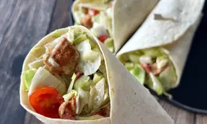Pyszna tortilla z kurczakiem, chrupiącą sałatą, pomidorkami i kremowym sosem. Idealna na szybki lunch.