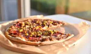 Pyszna pizza z kukurydzą i salami, dzieło mistrza pizzaiolo, leży na papierze.