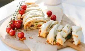 Ein köstlicher Stromboli, gefüllt mit Tomaten, Oliven und Käse, wird mit frischen Kirschtomaten garniert. Perfekt zum Stromboli essen!