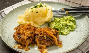 Två saftiga pannbiffar i ugn med karamelliserad lök, serverade med krämigt potatismos och gurksallad. En klassisk svensk rätt.