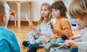 Kinder in der Kita lauschen gespannt einer Klanggeschichte und spielen mit Instrumenten.