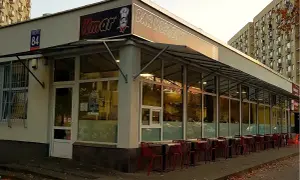 Bar mleczny Kmar z czerwonymi krzesłami przed wejściem.