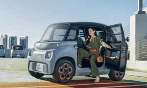 Donna scende da una Citroën Ami, un veicolo elettrico compatto. Le sue prestazioni sono ideali per la città.