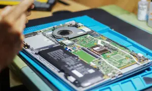 Naprawa laptopa. Widać płytę główną z baterią, wentylatorem i modułami, być może porównanie NGFF vs NVMe.