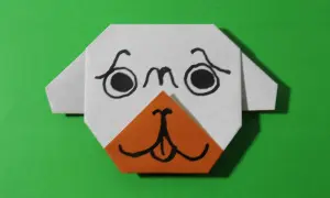 Uroczy origami piesek z pomarańczowym noskiem i czarnymi oczkami. Prosty origami piesek krok po kroku.