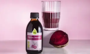 Butelka zakwasu z buraków Olini, szklanka z napojem i połówka buraka. Zastanawiasz się, ile zakwasu z buraka dziennie?