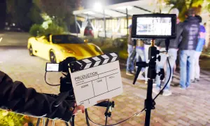 Na planie filmowym, gdzie kręcono scenę z żółtym sportowym autem, klaps filmowy zapowiada, ile zarabiają statyści na planach filmów Patryka Vegi i innych hitów.