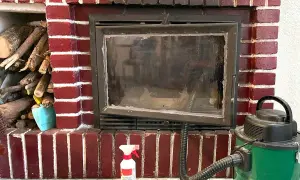 Preparativos para como deshollinar una chimenea: leña, aspiradora y spray limpiador.