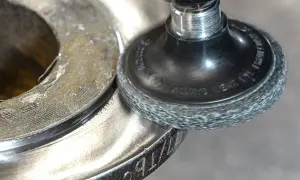 Obróbka wykańczająca metalowej części za pomocą szczotki drucianej. Widać ślady pracy narzędzia i przygotowanie do dalszych etapów.
