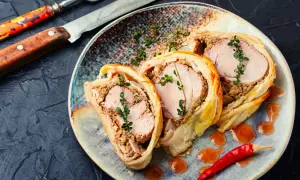 Pyszne ciasto francuskie na obiad, z soczystym mięsem i farszem, ozdobione gałązkami tymianku i papryczką chili.