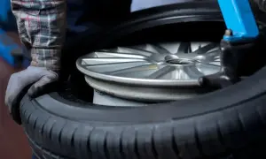 Mechanik w warsztacie wymienia oponę na feldze. Zastanawiasz się, ile kosztuje wymiana opon?