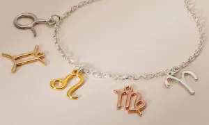 Bransoletka z zawieszkami w kształcie znaków zodiaku. Niektóre zawieszki mają piękne kolory złota, inne są srebrne lub w odcieniu różowego złota.