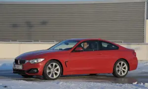 Czerwone BMW F32 435i z kierowcą za kierownicą, zaparkowane na śniegu przed budynkiem.