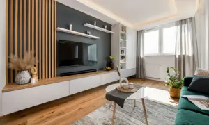 Nowoczesna ściana w salonie z drewnianymi lamelami, telewizorem i białymi szafkami. Idealne co na ścianę w salonie, by nadać wnętrzu charakteru.